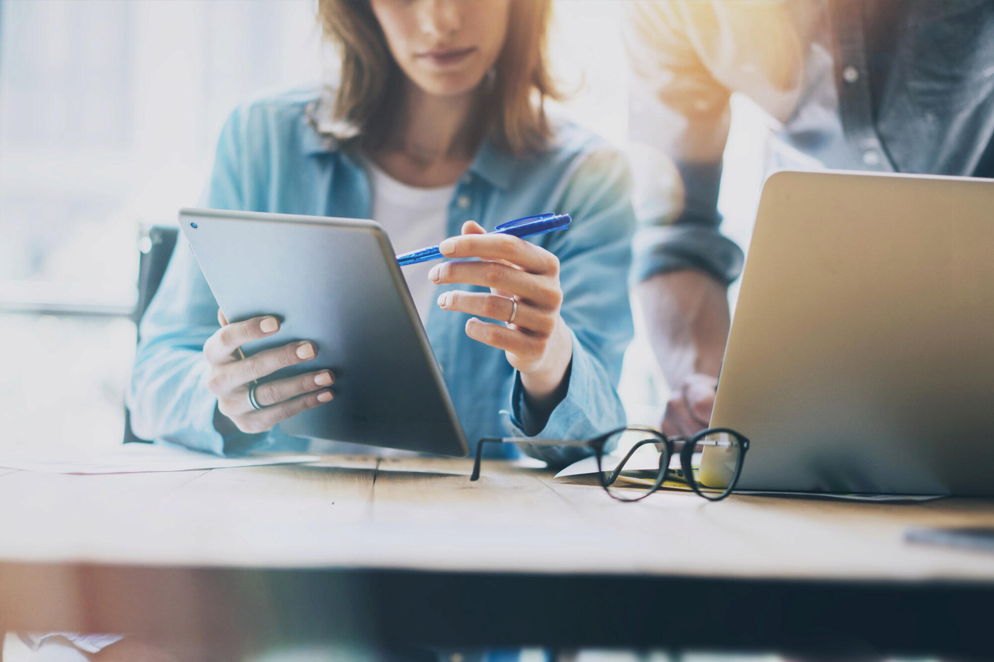 Femme montrant son travail sur sa tablette à un collègue de travail